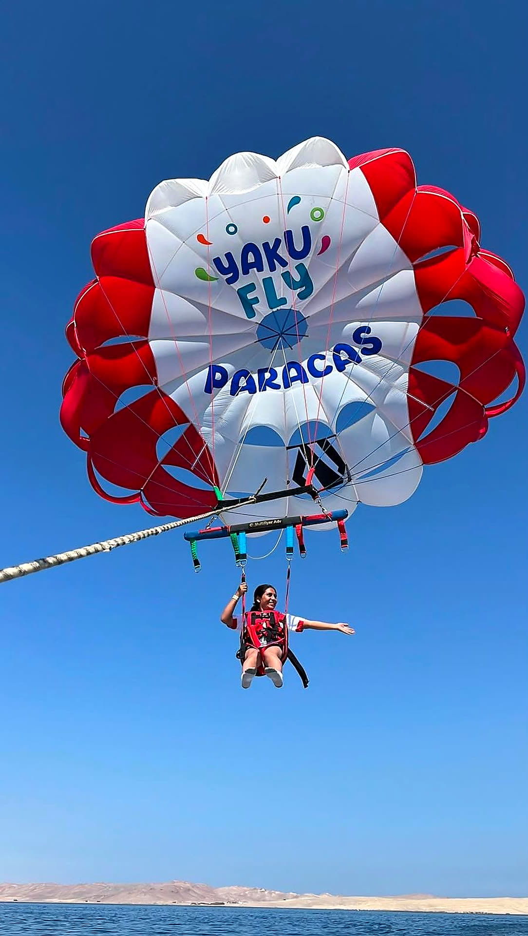 Pasajeros disfrutando su vuelo de parasailing en Paracas con vista al desierto y el mar